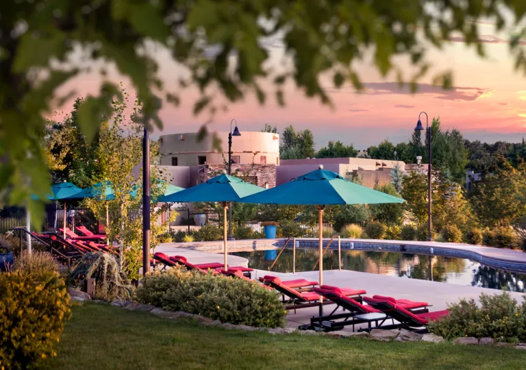 Outdoor pool with blue umbrellas and red chairs