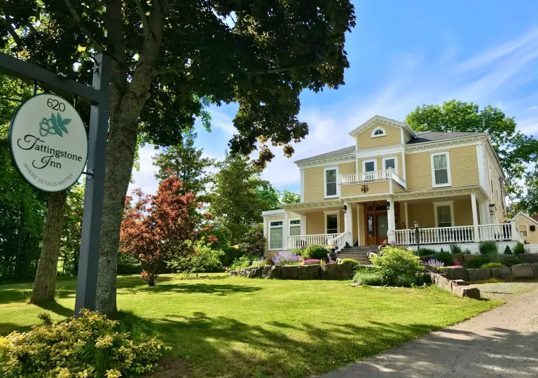 Exterior view of yellow building with a grass area in front, surrounded by trees