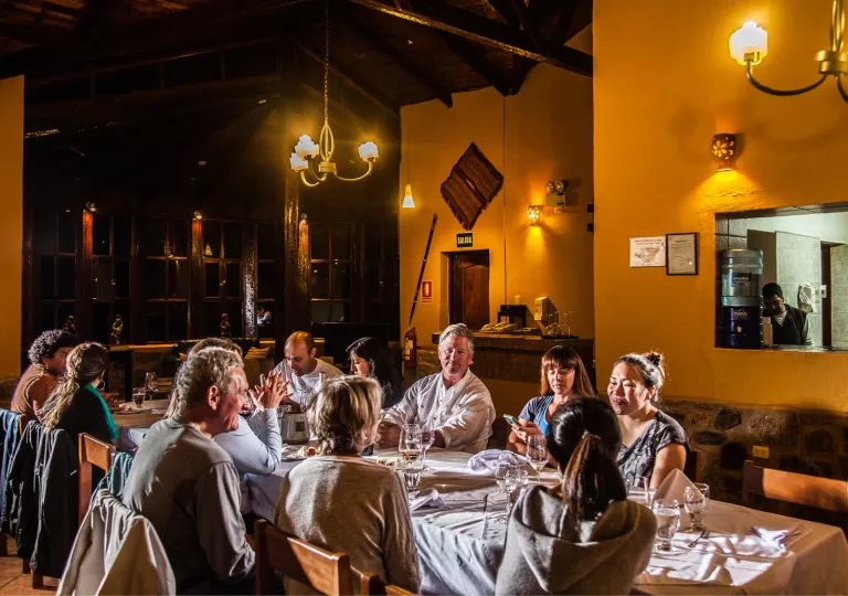 Group of people sitting at a long, rectangular dining table sipping on glasses of wine