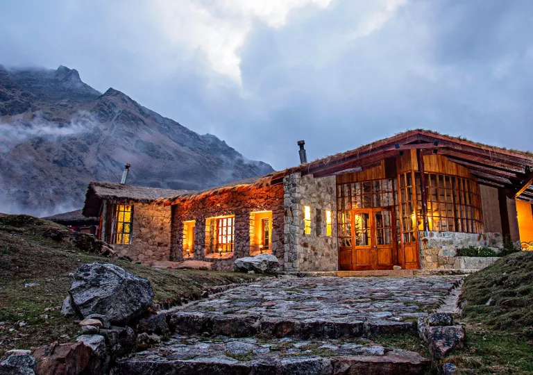 Stone building with warm lights inside, with foggy mountains in the background