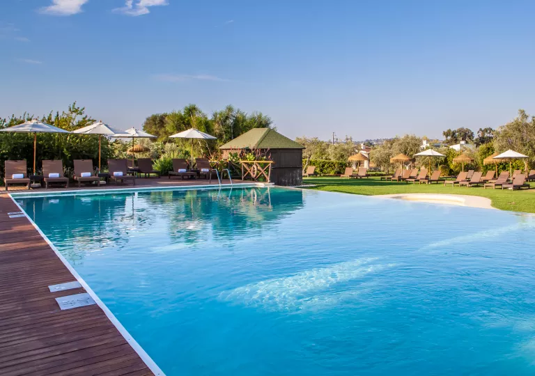 Outdoor swimming pool surrounded by a wooden plank walkway and wooden reclining chairs