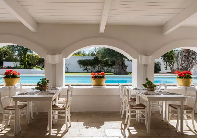Outdoor dining area with white archways, and flowers sitting on top of each table