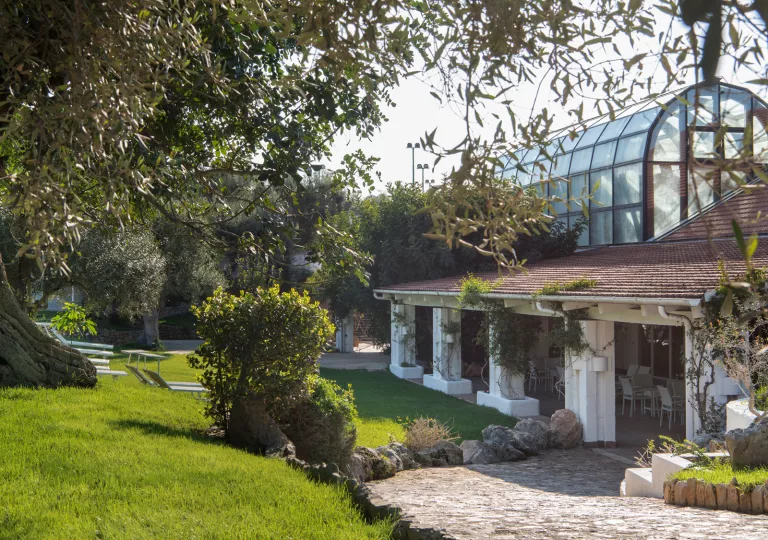 Exterior view of building with a greenhouse on the top floor, with a garden in front