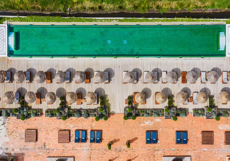 Sky view of outdoor pool with umbrellas and chairs on one side