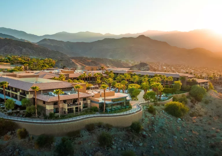 Outdoor view of hotel on a cliff, with palm trees