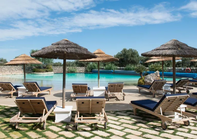 Outdoor pool with navy blue pool chairs and hay umbrellas