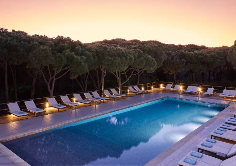 Outdoor pool surrounded by white pool chairs
