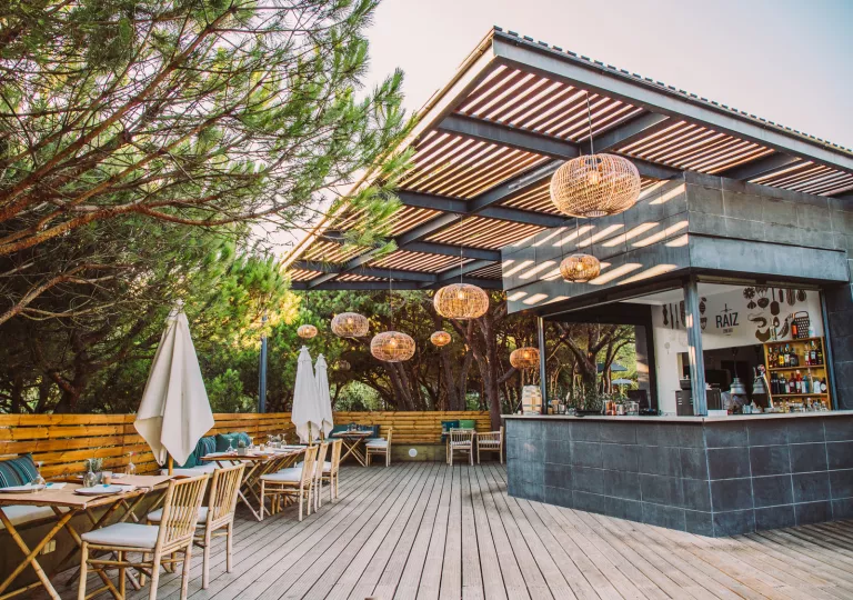 Outdoor bar with woven ceiling light fixtures and wooden chairs