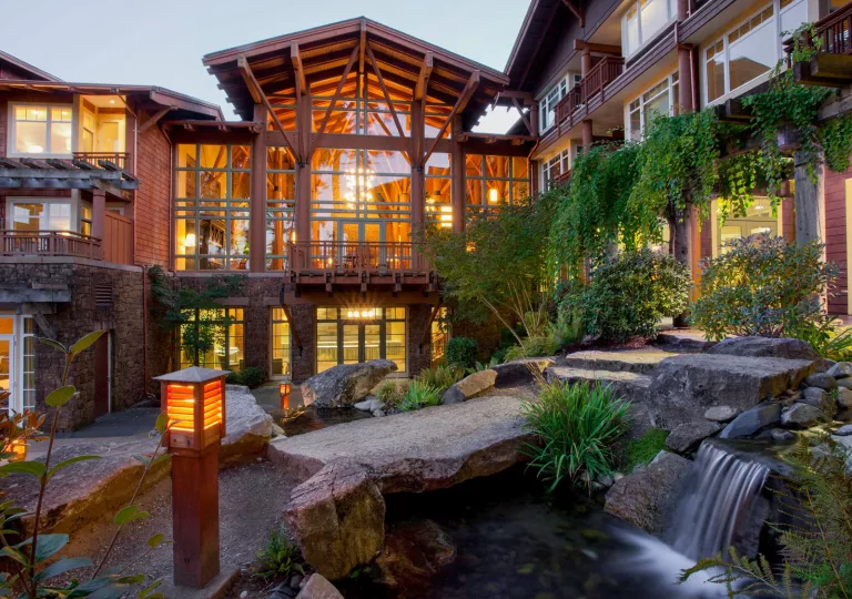 Wooden building with large windows and a mini, outdoor waterfall made of rocks
