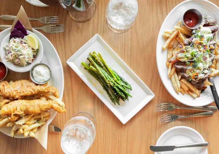 Plates of asparagus, fish and chips, and fries