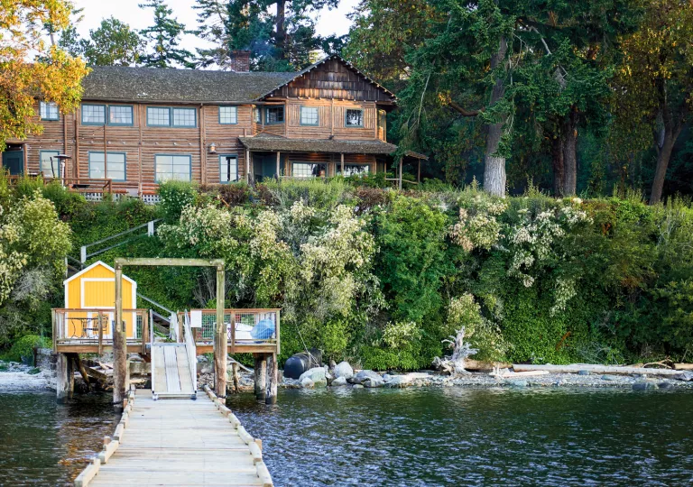 Exterior view of a wooden lodge building above, with a lake and bridge under