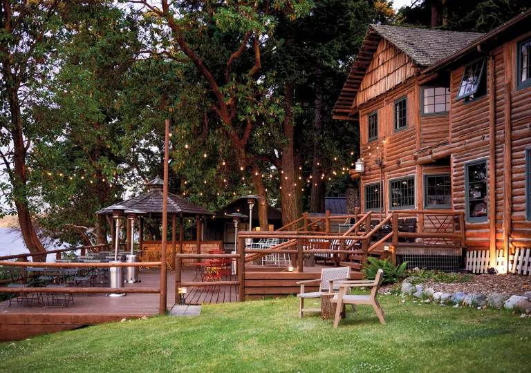 Exterior view of cabin-style building with a wooden patio and string lights