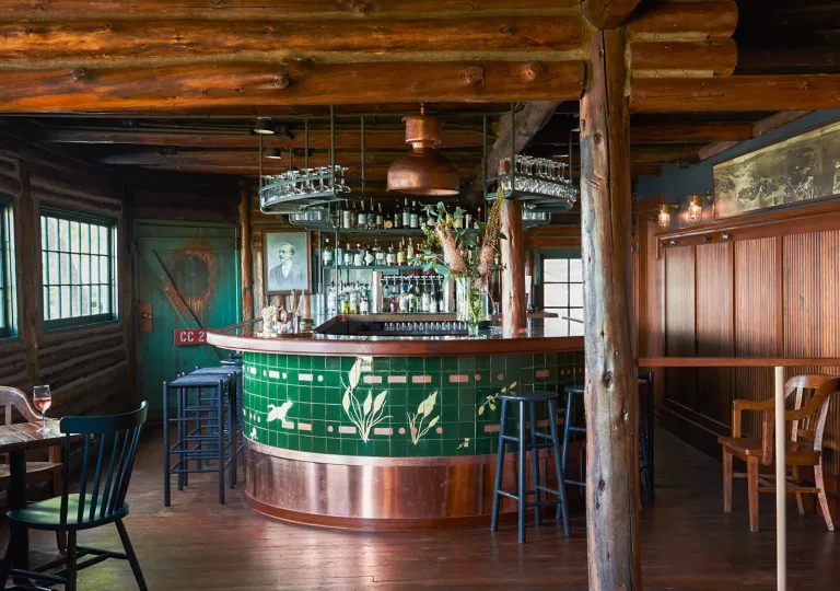 Indoor bar counter surrounded by blue stools, with wooden pillars around the room