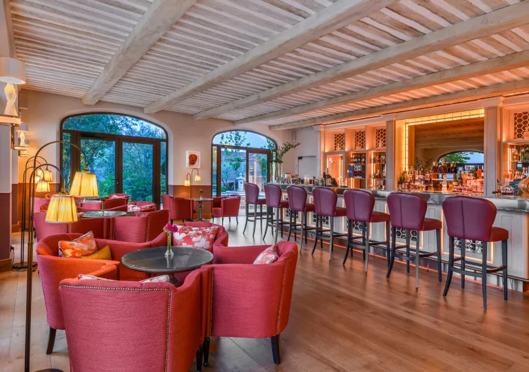 Bar and lounge filled with red cushioned chairs and stools