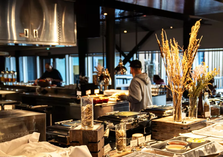 Indoor dining hall with food warmers, as people are serving plates of food