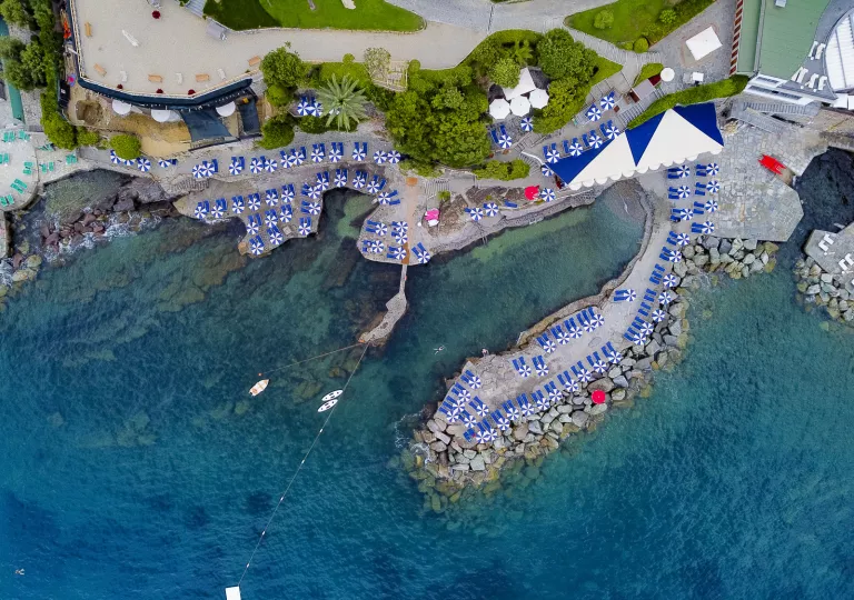 Sky view of a port with blue chairs and umbrellas next to the water