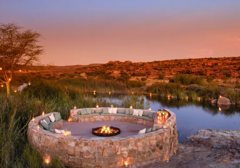 A circular seating area with a fire pit in the center, overlooking mountains and canyons