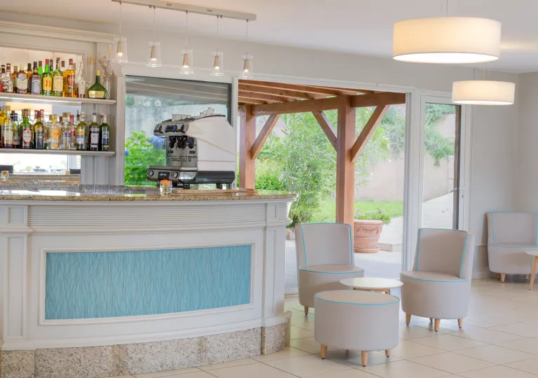 Bar with liquor on the wall and circular tables and chairs to the right
