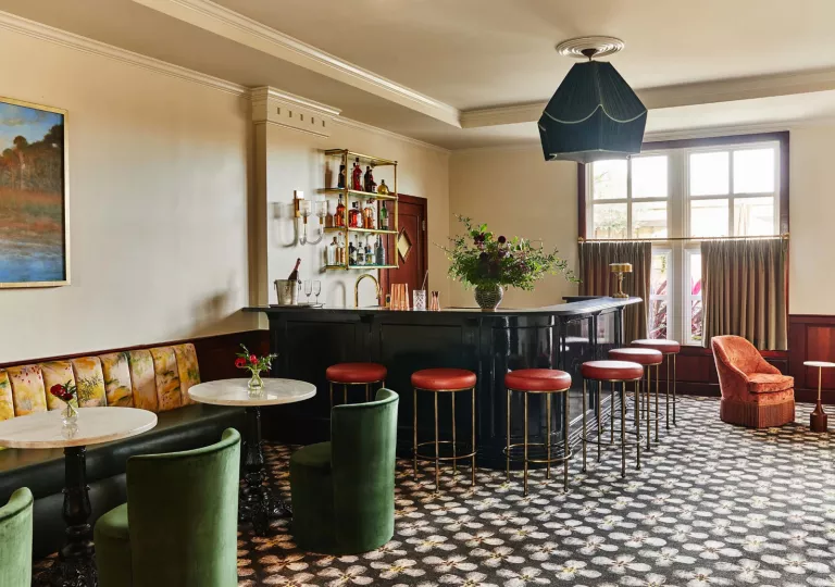 Indoor bar and lounge, with green cushioned chairs and red bar stools