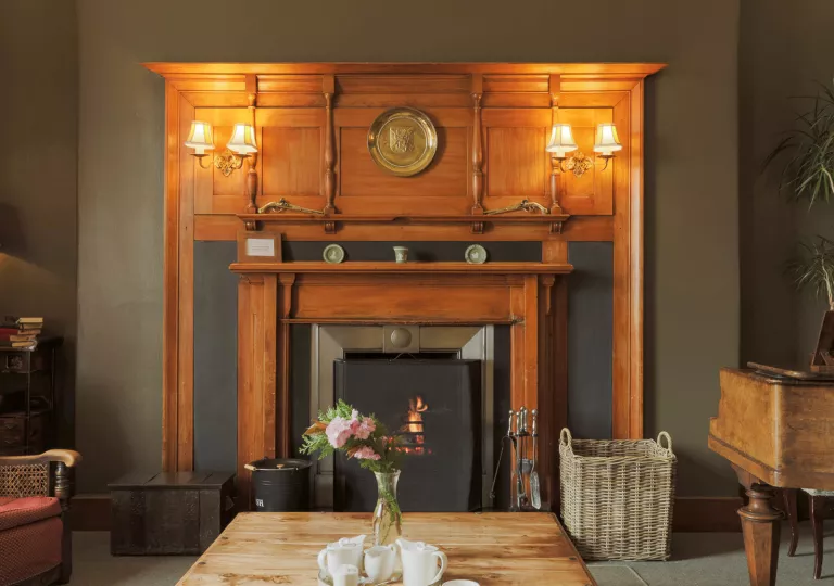 Carved wooden fireplace with a wooden table in front