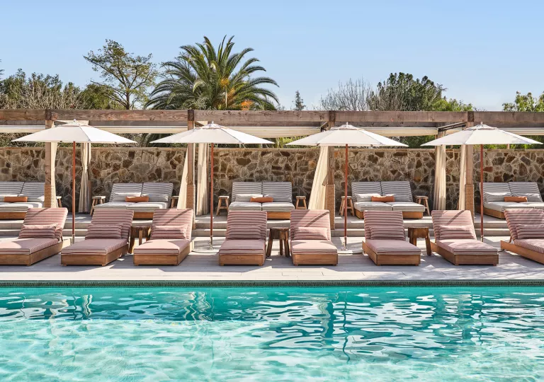 Outdoor pool with cushioned pool chairs and white umbrellas