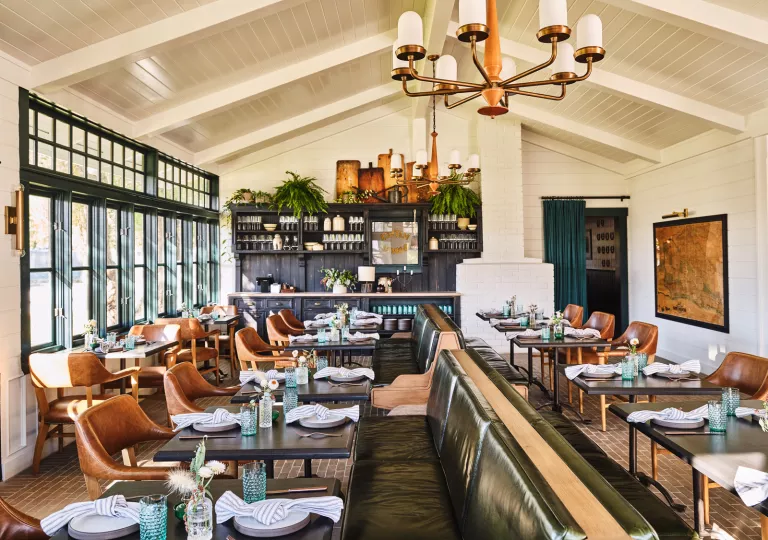 Dining area with green and brown leather sets and folded handkerchiefs on the tables