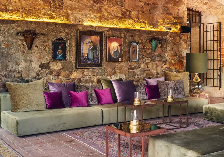 Indoor seating area with long, green sofas and purple pillows