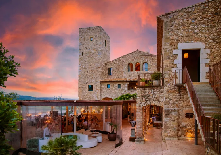 Stone, rustic building with a covered bard and seating area on the ground floor
