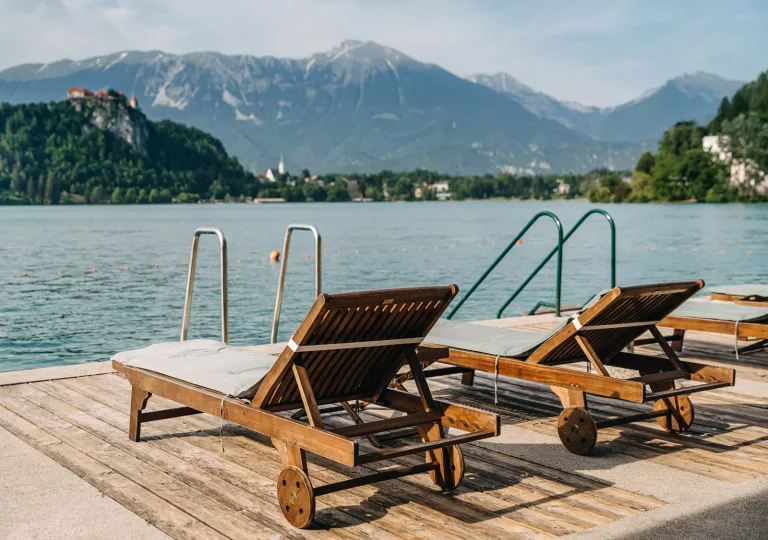 Two wooden lounge chairs on a deck overlooking the water