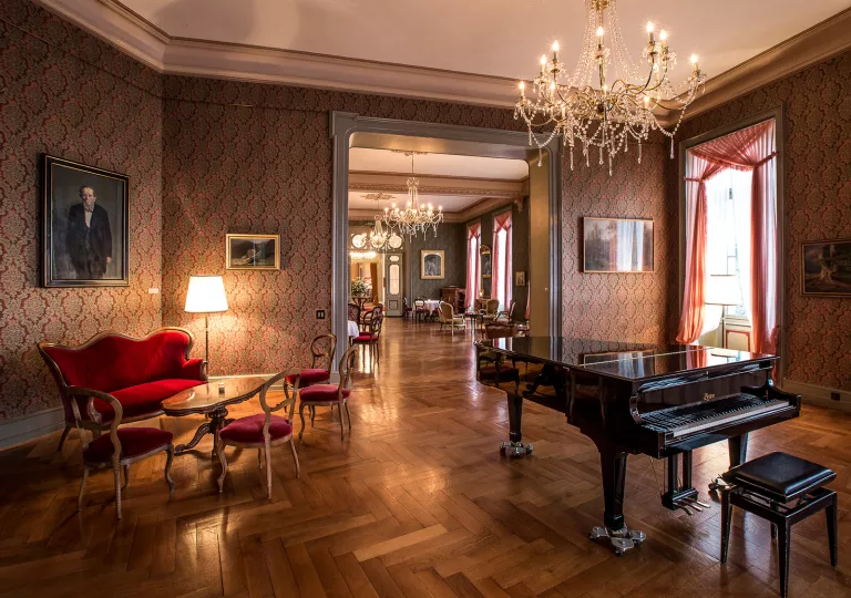 Indoor lobby with red, cushioned chairs and a piano on the right