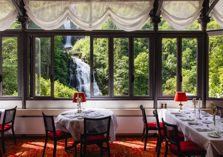 Indoor dining area with large windows looking out to a waterfall