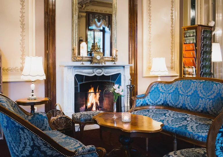 Indoor lounge with blue, cushioned chairs in front of a fireplace