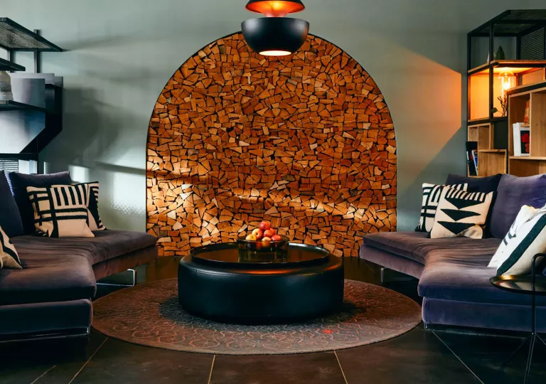 Indoor waiting area with blue sofas and a wooden art piece on the wall