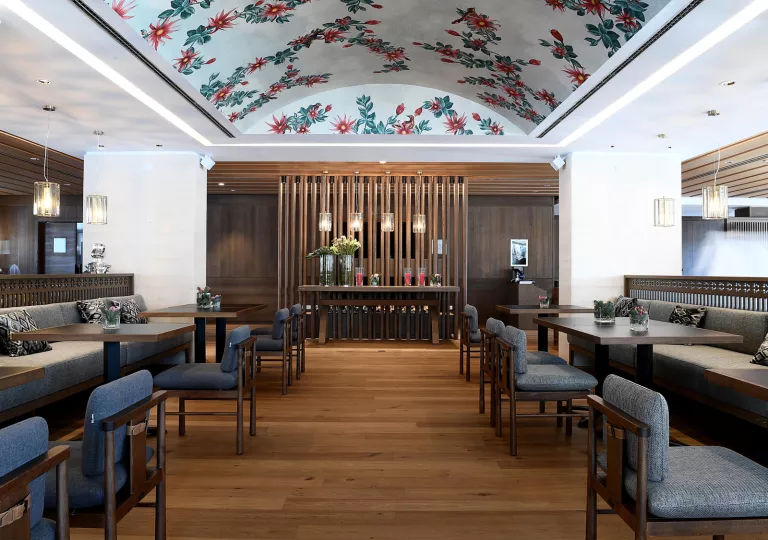 Indoor dining area with square tables and plants on each table