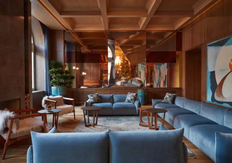 Indoor lounge with blue, cushioned seats and paintings on the wall