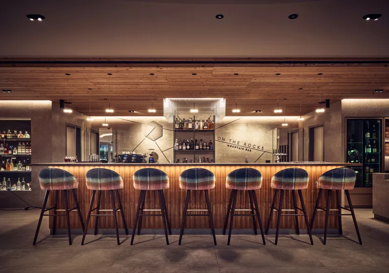 Indoor bar and lounge, with an illuminated bar counter and brown bar stools