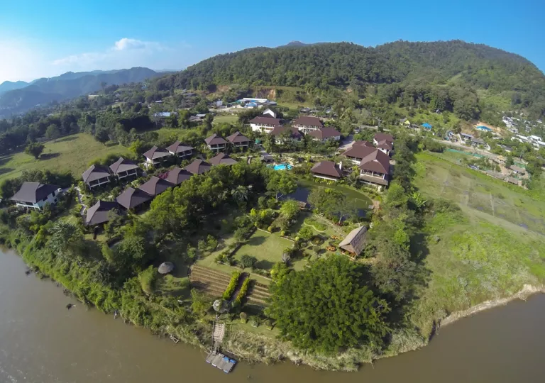 Sky view of tan buildings with brown roofs next to a lake and open valley