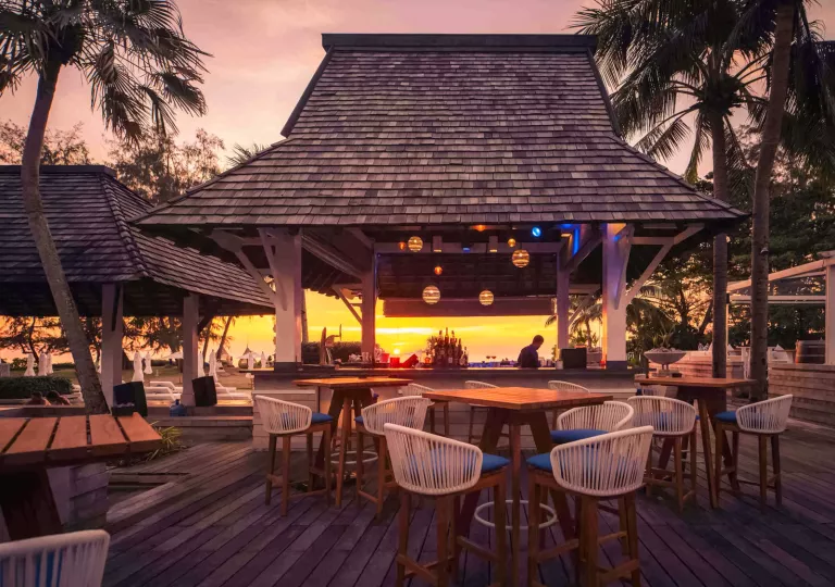 Outdoor huts with woven chairs and wooden tables
