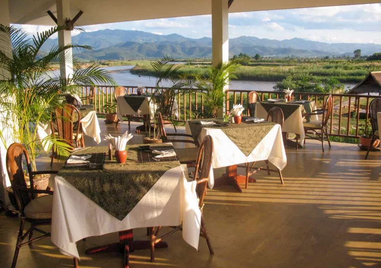 Outdoor patio dining area with a view of an open valley and lake in the distance