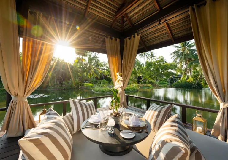 Outdoor hut with large curtains with a circular table and pillows under the hut