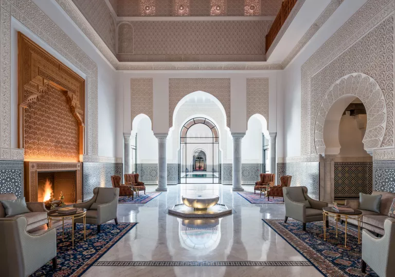 Hotel lobby with marble flooring and large stone pillars under an archway