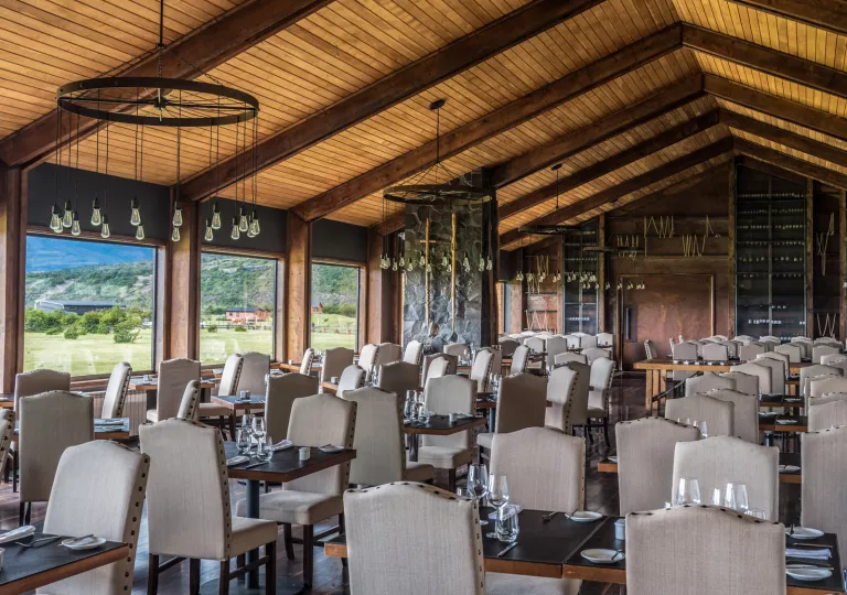 Dining hall filled with tables and white cushioned chairs