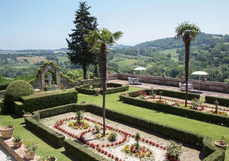 Outdoor garden with trimmed bushes, and stone barricades and statues