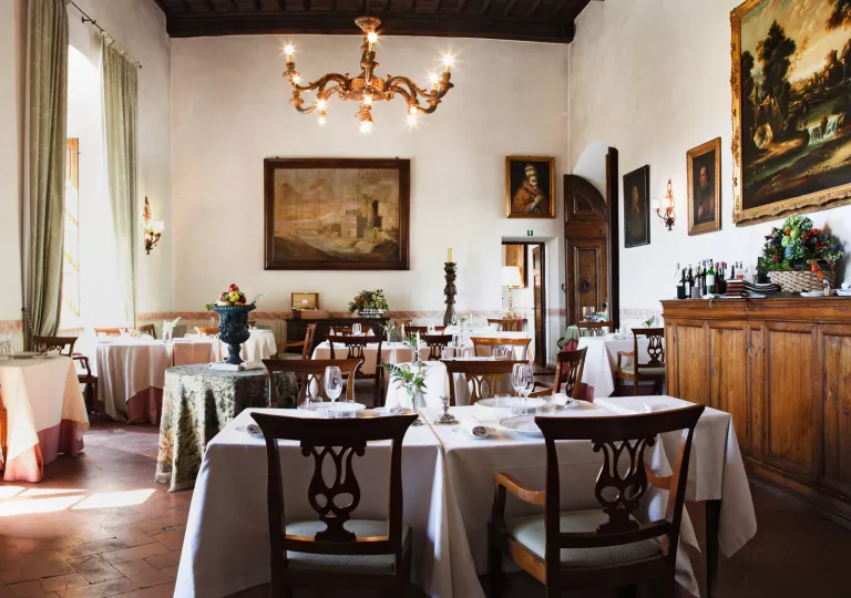 Indoor dining area with white tablecloths and a candle chandelier on the ceiling