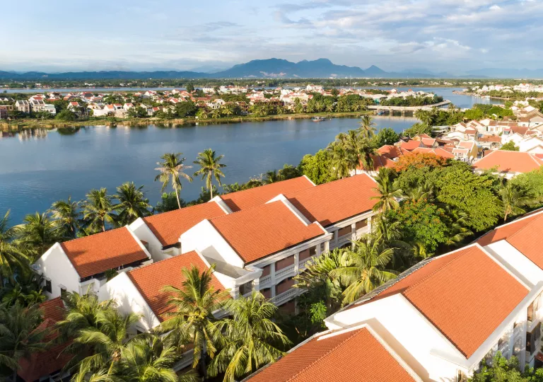 Rows of white buildings with orange roofs, looking out towards a small lake