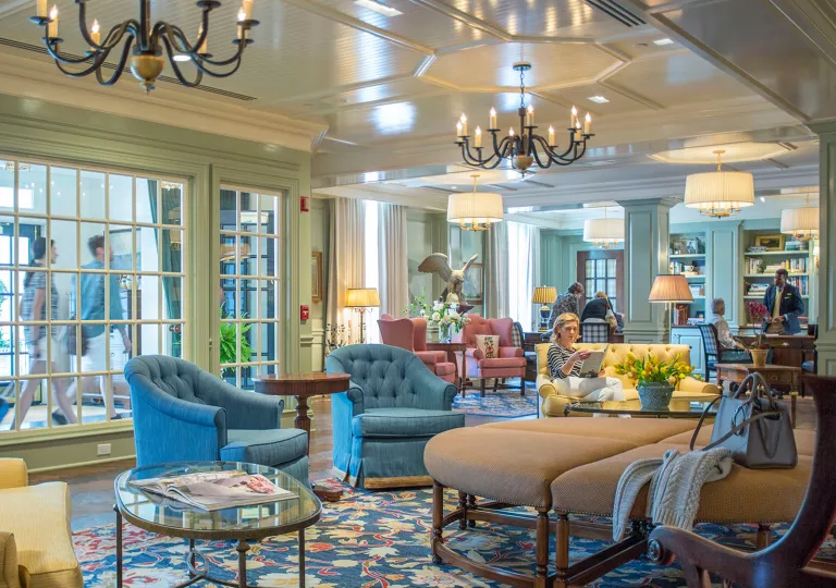 Hotel lobby with large cushioned seats, with people sitting down and reading