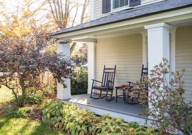 Black rocking chairs in front of a white house