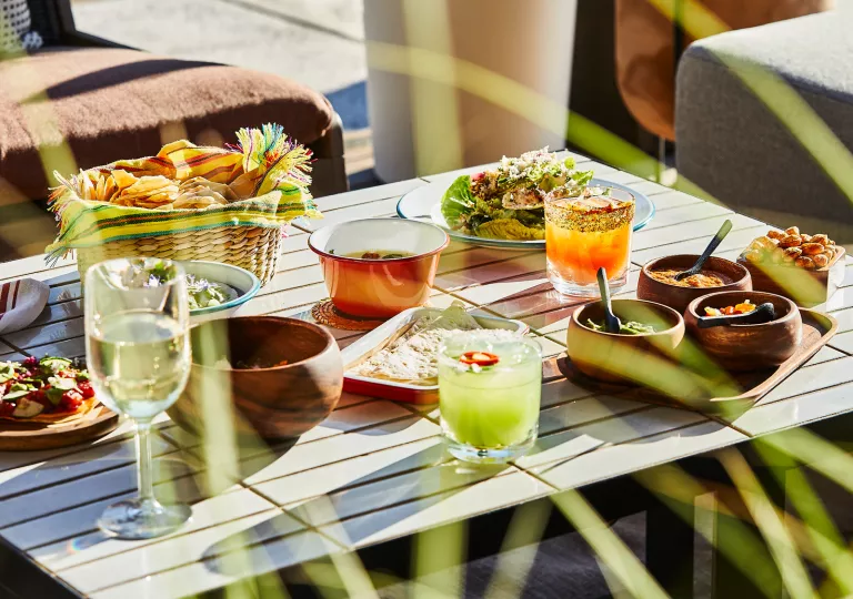Outdoor table full of food and alcoholic drinks