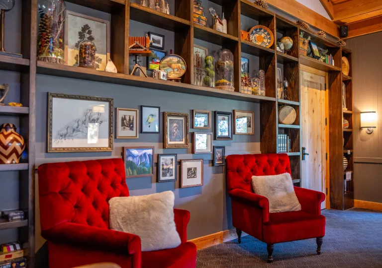 Two red chairs in front of a wall full of paintings and antique trinkets