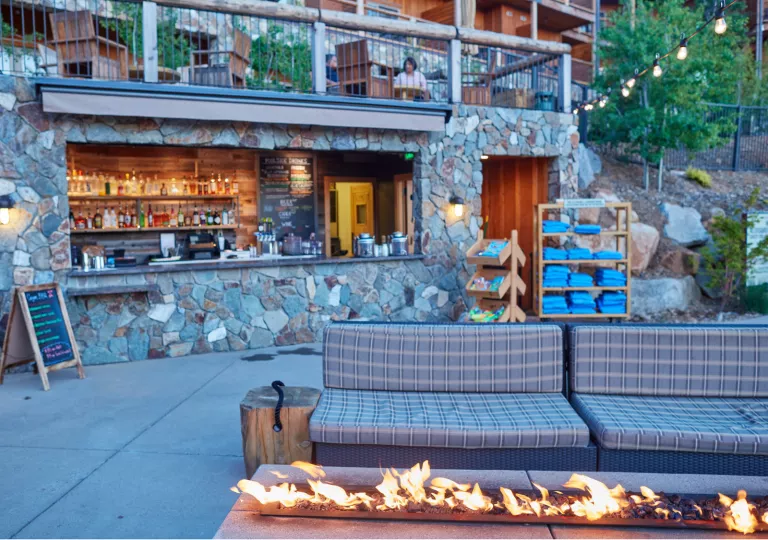Outdoor bar area with a stone wall and a sofa in front of a stone fire pit